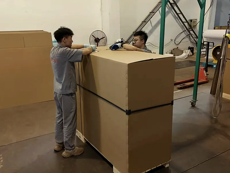 Two Angel Musical staff strapping a cardboard piano crate on a pallet