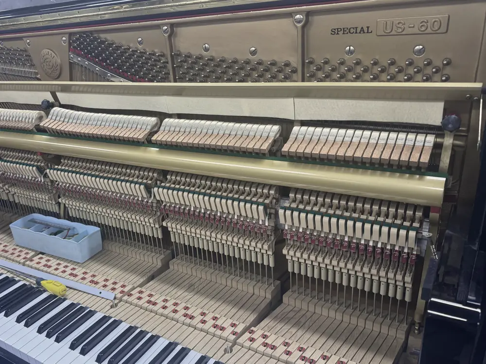 Open upright piano with action and keys exposed during reconditioning